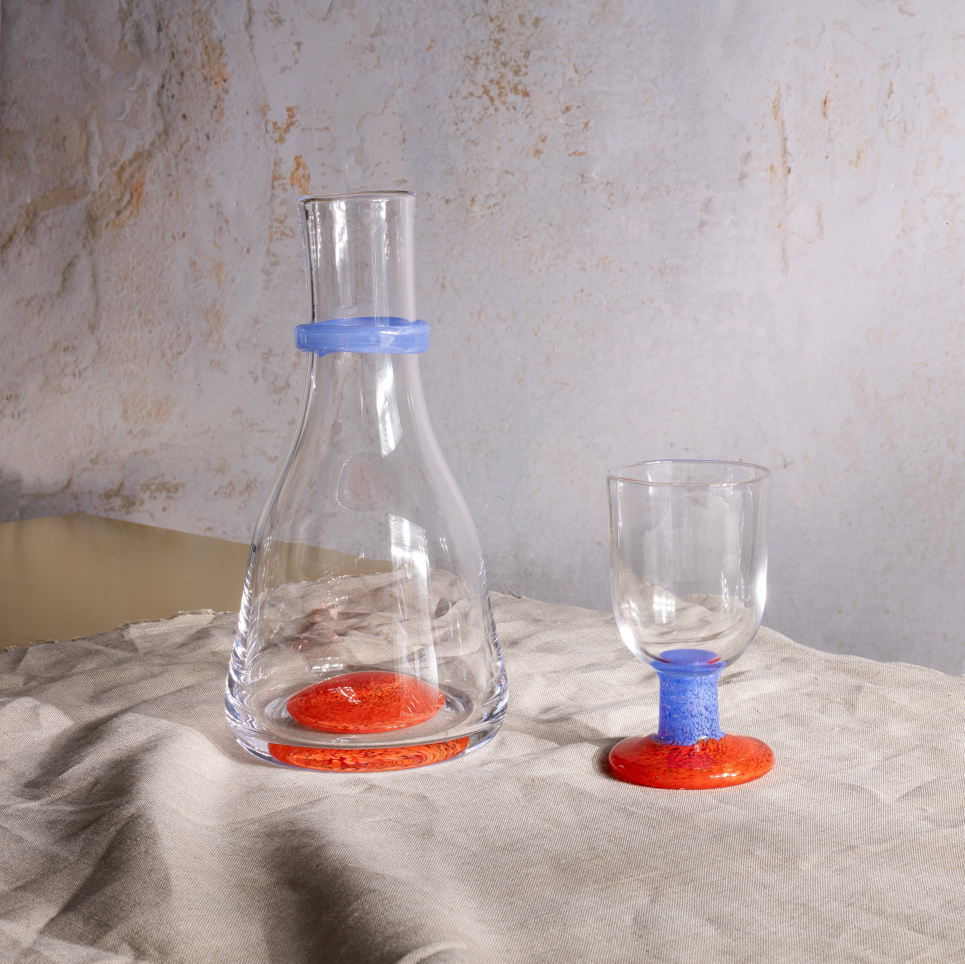 Two glass containers with colorful bases on a textured surface